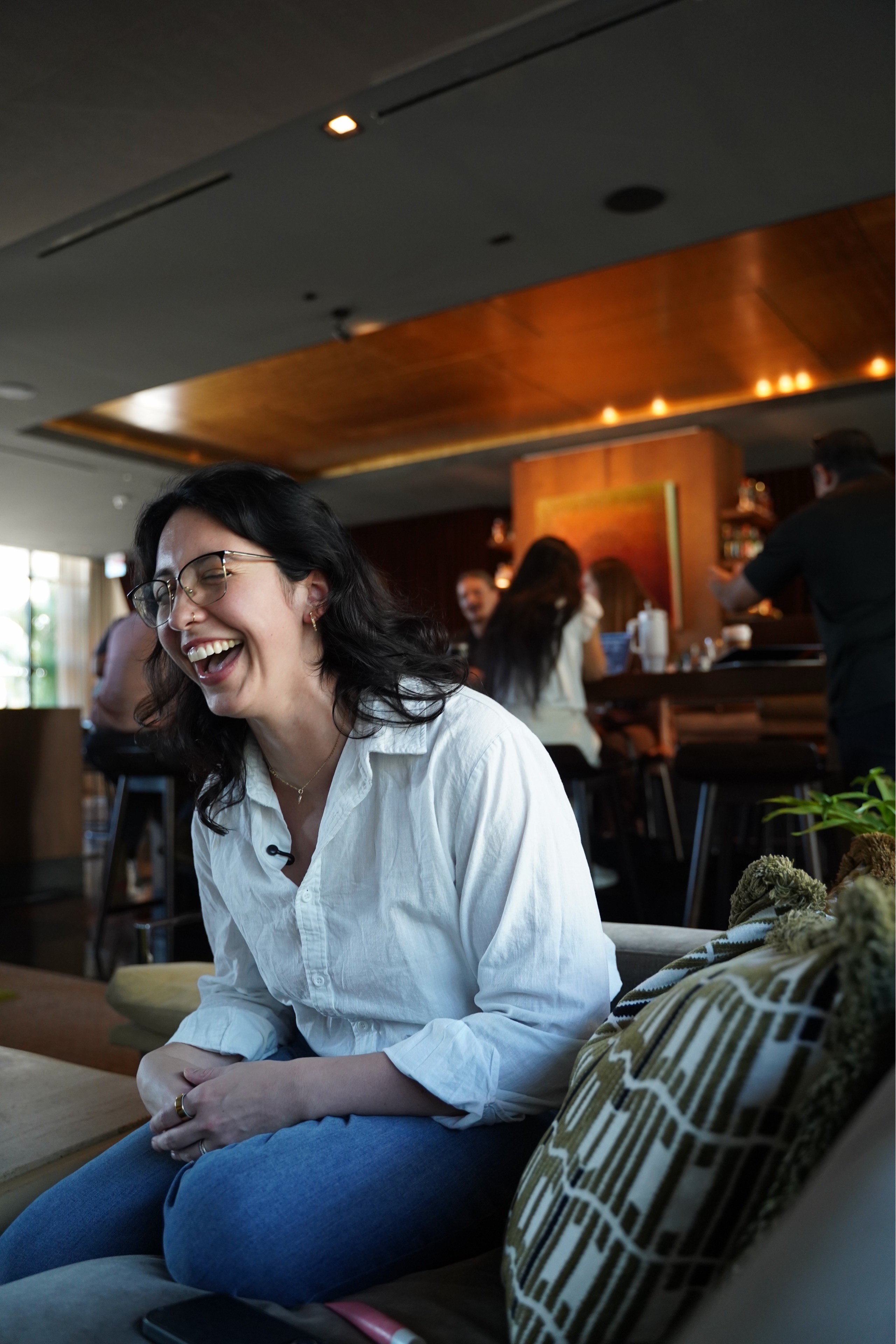 Alyssa laughing during a relaxed conversation, seated on a sofa.